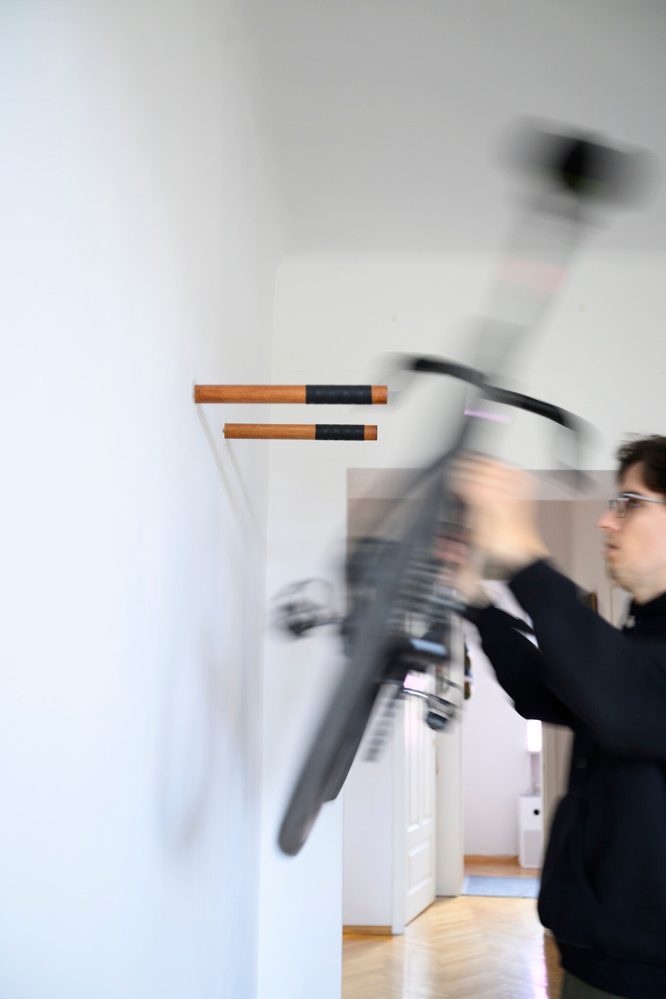 Person installing a bicycle on a wall-mounted stand in a room.
